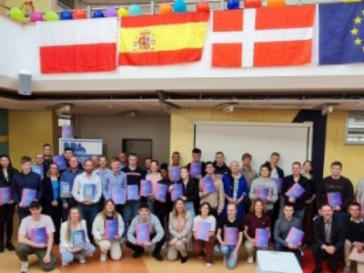 Gruppenfoto von Schülern der BBS Buxtehude mit Europass-Mappen und Fahnen europäischer Länder im Hintergrund