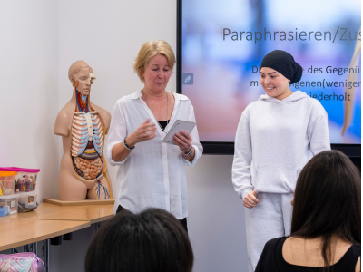 Lehrerin mit Schülerinnen und Schülern im Unterricht im Rahmen der neuen Pflegeausbildung